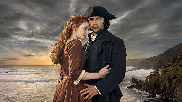 A man in a black tricorn hat and coat embraces a red-haired woman in a brown dress by a stormy sea.