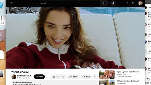 A woman with long brown hair smiles while sitting on a white couch, displayed on a web browser.