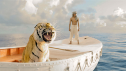 A tiger roars in a white boat on the ocean while a man stands in the background under a cloudy sky.