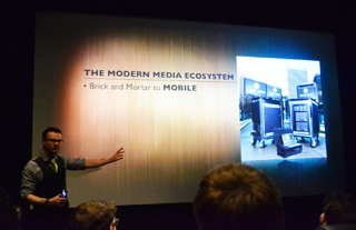 A man in a vest gestures toward a presentation slide titled 'THE MODERN MEDIA ECOSYSTEM'.