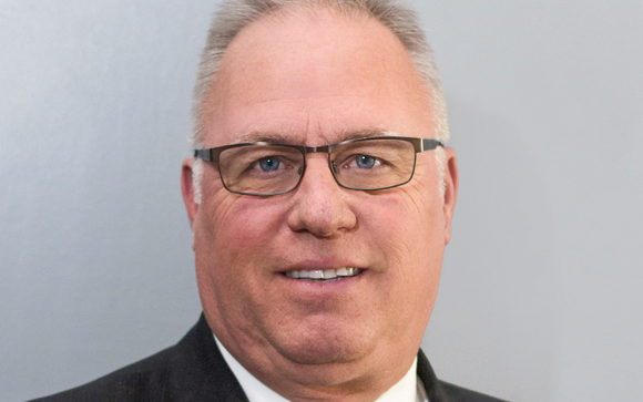 A smiling man with short light hair and glasses looking directly at the camera.