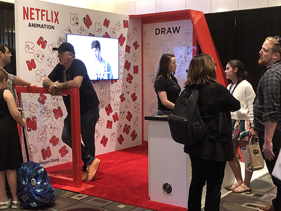 People gather around a Netflix Animation booth with a drawing area and a screen displaying animation.