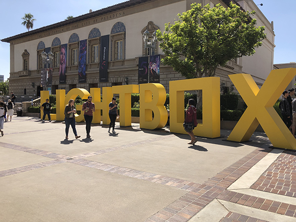 Giant yellow letters spelling LIGHTBOX in front of the Pasadena Civic Auditorium with people walking around.