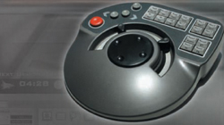 A gray handheld electronic controller with a large central dial, a red button, and several small gray buttons.