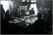 A group of people sitting around a long table in a dark, indoor setting.