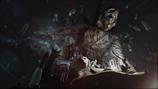 A dark, textured humanoid figure towers over a small, detailed model of a city in a dark, debris-filled space.