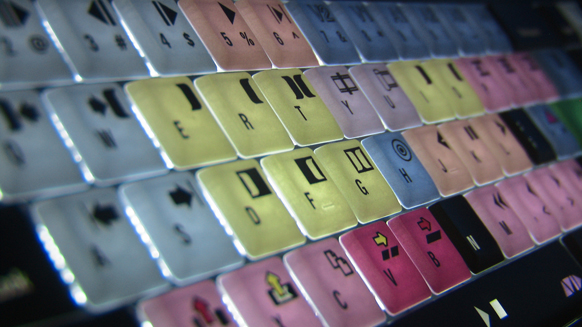 Extreme close-up of colorful, backlit mechanical keyboard keys with various letters and symbols.