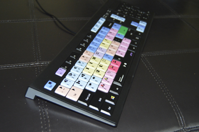 A black computer keyboard with various colored keys resting on a dark leather surface.