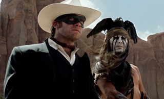 A man in a white cowboy hat and black mask stands beside a person in indigenous-style ceremonial attire.