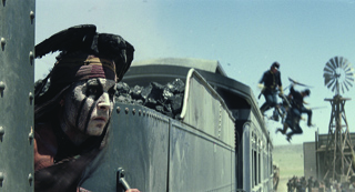 A person with black face paint and a feathered headpiece looks out from a moving train car.