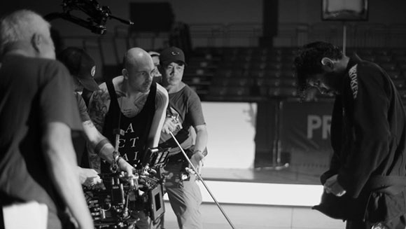A black and white shot of a film crew operating a camera and equipment on a production set.