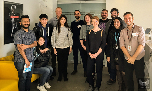 A diverse group of ten people standing together and smiling in an indoor setting.