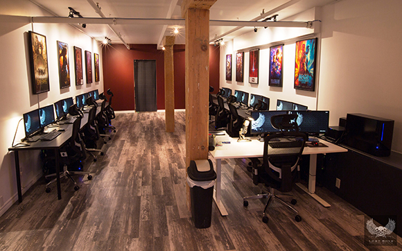 A long room with two rows of computer desks, black chairs, and colorful posters on the walls.
