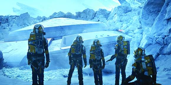 Four astronauts in yellow suits stand before a large white spacecraft inside a blue-tinted ice cave.