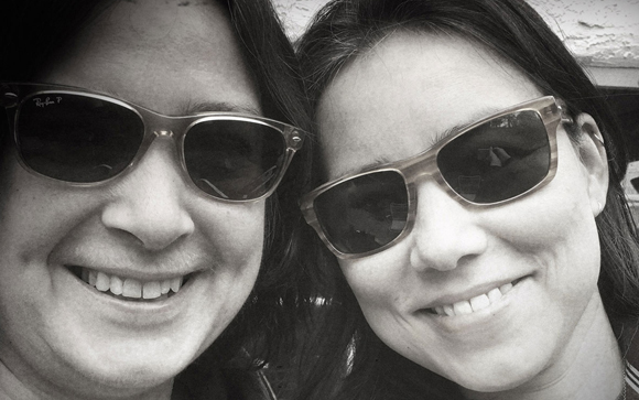 Black and white close-up of two people smiling while wearing sunglasses.