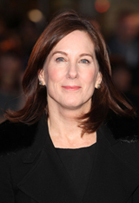 A woman with shoulder-length brown hair and blue eyes smiling slightly while wearing a black coat.
