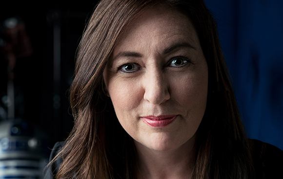 A woman with long brown hair and dark eyes looks directly at the camera.
