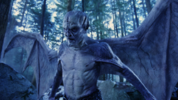 A pale, muscular humanoid creature with large bat-like wings standing in a dense forest.