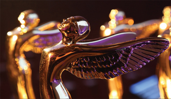 Close-up of several shiny, golden winged statues with a blurred dark background.