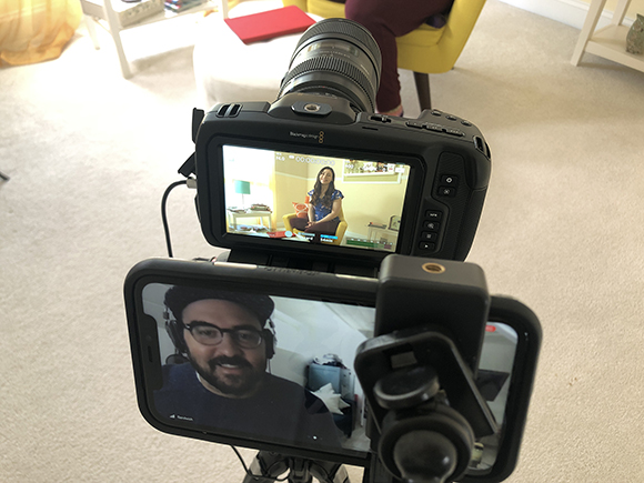A DSLR camera and a smartphone on a tripod both showing video call interfaces with different people.