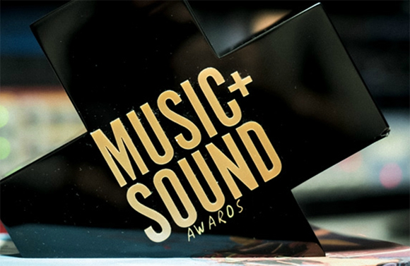 A black cross-shaped trophy with gold text reading 'MUSIC+SOUND AWARDS'.