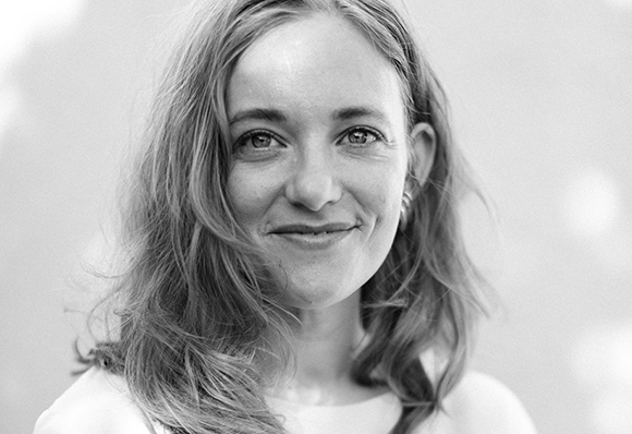 Black and white close-up portrait of a smiling woman with wavy hair looking toward the camera.
