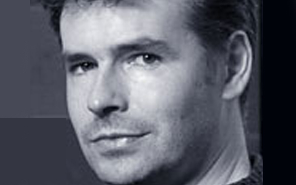 A close-up, black and white portrait of a man looking slightly off-camera.
