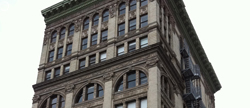 Low-angle view of a multi-story historic stone building with arched windows and decorative cornices.
