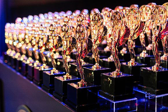A row of many gold-colored winged trophies on black rectangular bases.
