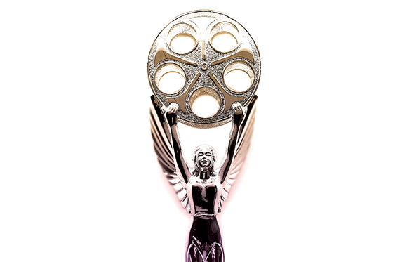 A silver trophy of a winged woman holding a large film reel above her head against a white background.