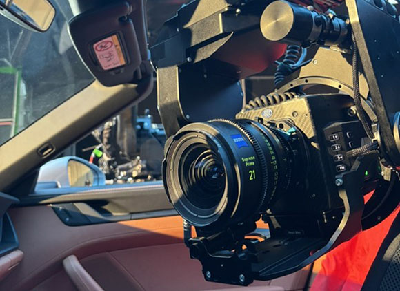 A large professional cinema camera with a large lens mounted inside a car.