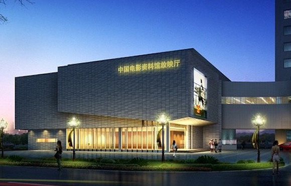 A large, modern gray building with glowing yellow text and bright street lamps under a twilight sky.