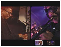 A man smiling in a dark suit and a man playing a wind instrument under purple light.