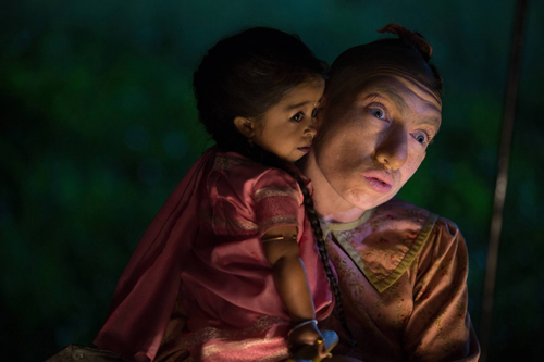 A young child with dark hair embraces an older person in a dimly lit setting.