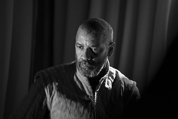 Black and white portrait of a bearded man looking to the side in dramatic lighting.
