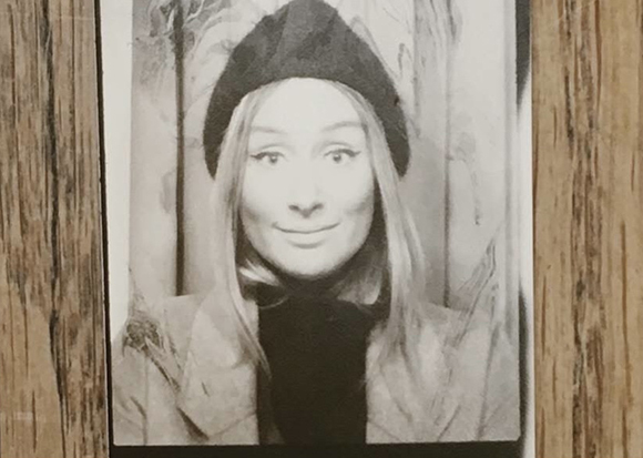 Black and white portrait of a woman with long hair wearing a dark beanie and a jacket.