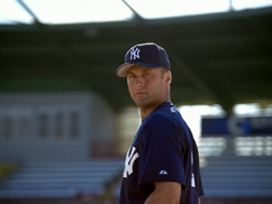 A man wearing a navy blue Yankees baseball cap and jersey looks back over his shoulder.