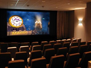 Rows of empty theater seats facing a large screen displaying a cartoon clock and the word MAGNO.