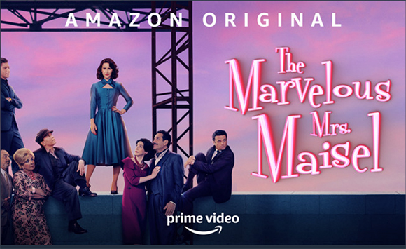 Cast members of The Marvelous Mrs. Maisel posing against a pink sunset sky.