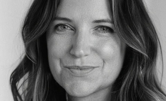 A black and white close-up portrait of a woman with wavy hair smiling slightly.