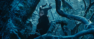 A woman with large black horns looks through snow-covered tree branches in a dark, blue-toned forest.
