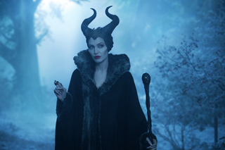 A woman with large black horns and a dark fur-trimmed cloak stands in a misty, blue-toned forest.
