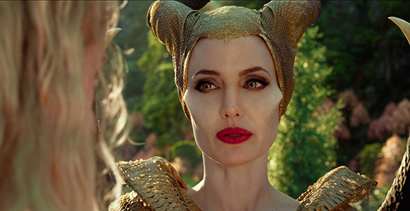 A woman with large, textured golden horns and bright red lipstick looks forward with a serious expression.