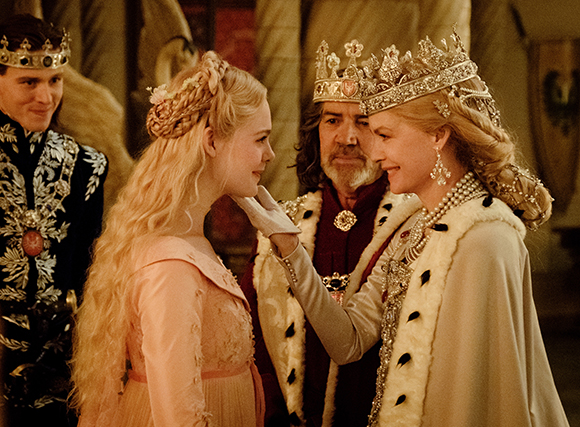 A young blonde woman in pink receives a hand kiss from an older queen in white and pearls.