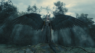 A woman with large black wings and horns stands in a foggy, dark forest.