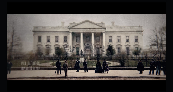 A group of people in 19th-century attire standing before the White House behind a black iron fence.