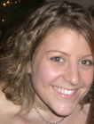 A smiling woman with wavy light brown hair looking toward the camera.