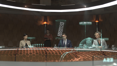 People sit around a circular table featuring glowing hexagonal patterns and floating holographic data projections.