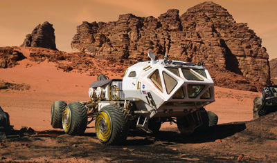 A white multi-wheeled planetary rover sits in a red desert landscape with large rock formations under an orange sky.