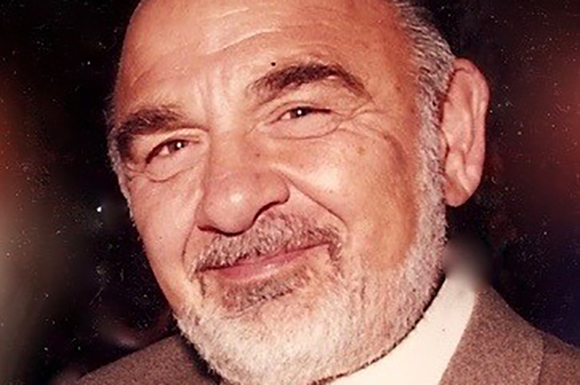 Close-up portrait of an elderly man with grey hair, a white beard, and a slight smile.